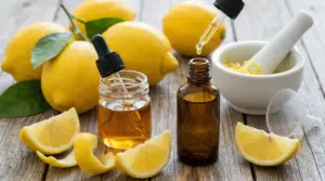 Olio essenziale di limone in bottigliette con pipette, limoni freschi e mortaio su tavolo di legno