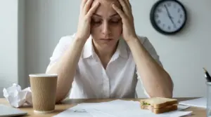 Persona seduta alla scrivania con le mani sulla testa in segno di stress