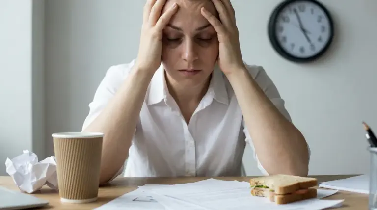 Persona seduta alla scrivania con le mani sulla testa in segno di stress