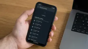 Una mano tiene uno smartphone che mostra file di grandi dimensioni da eliminare in WhatsApp.